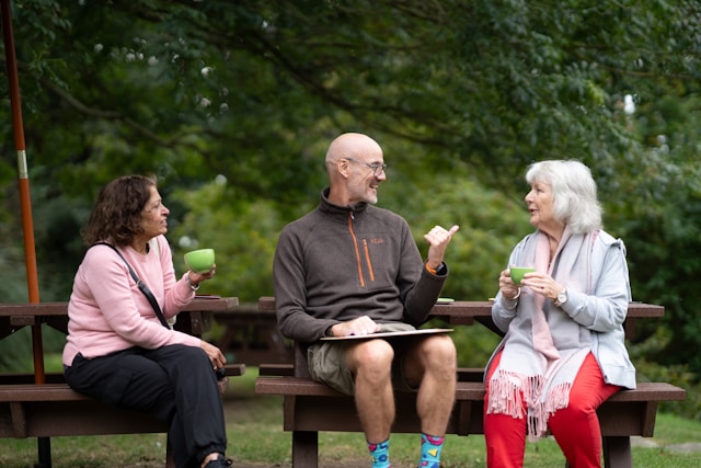 group sitting on a bench outside with coffee 